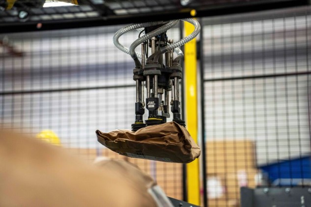 Brazo robótico automatizado manipulando paquetes en un centro logístico avanzado para optimizar la clasificación y distribución de envíos.