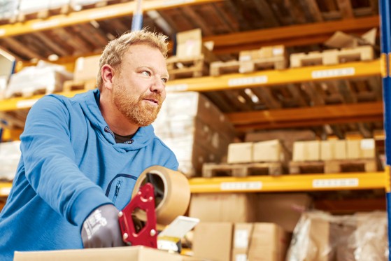 GLS worker taping a parcel in a warehouse