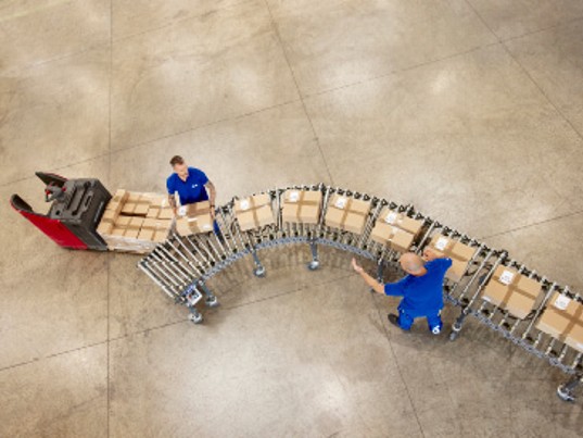 GLS employees handling parcels on a sorting line inside a logistics warehouse, illustrating operational procedures and compliance processes within the group.