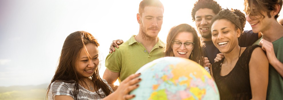 Multi-ethnic group of people observes a globe