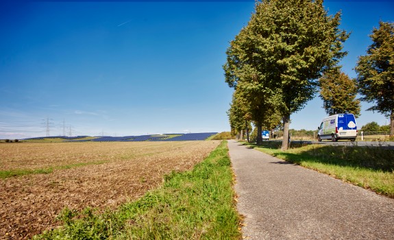 Elektrsiche GLS-bus door een landschap vol met zonnepanelen