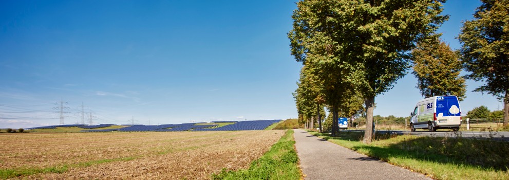 Elektrsiche GLS-bus door een landschap vol met zonnepanelen