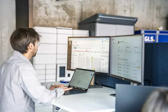 A man working on a computer with lines of code on the screen.